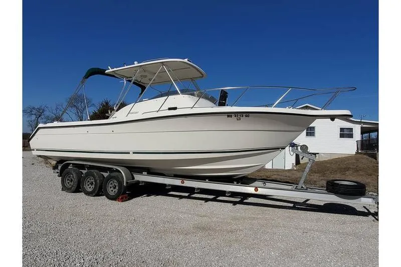 The Image of 1997 Pursuit 2800 Offshore boat on trailer, parked outdoors under clear blue sky. - 0