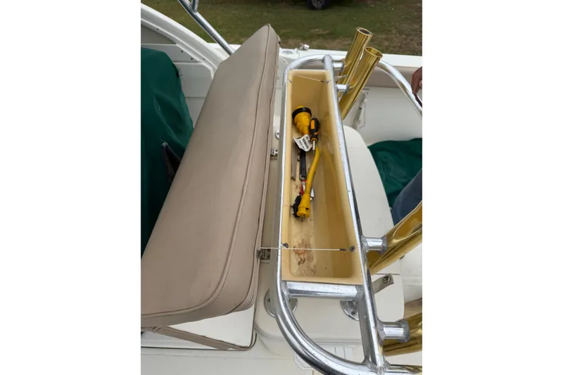 Slide: The Image of 1997 Pursuit 2800 Offshore boat storage compartment with tools and fishing rod holders. - 19