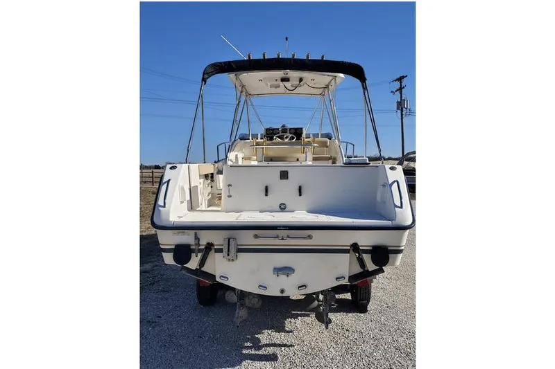 Slide: The Image of 1997 Pursuit 2800 Offshore boat, rear view, parked on gravel under clear blue sky. - 9