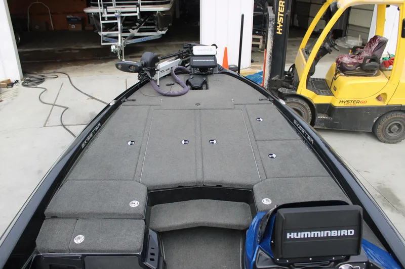 Slide: The Image of 2022 Skeeter ZX225 boat deck with Humminbird electronics, parked near a yellow forklift. - 4