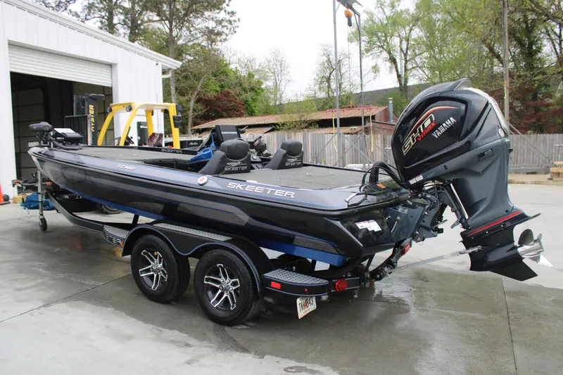 Slide: The Image of 2022 Skeeter ZX225 boat with Yamaha engine on trailer, parked outside a garage. - 7