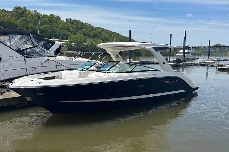 The Image of 2023 Sea Ray SLX 310 boat docked at marina, surrounded by water and greenery. - 1