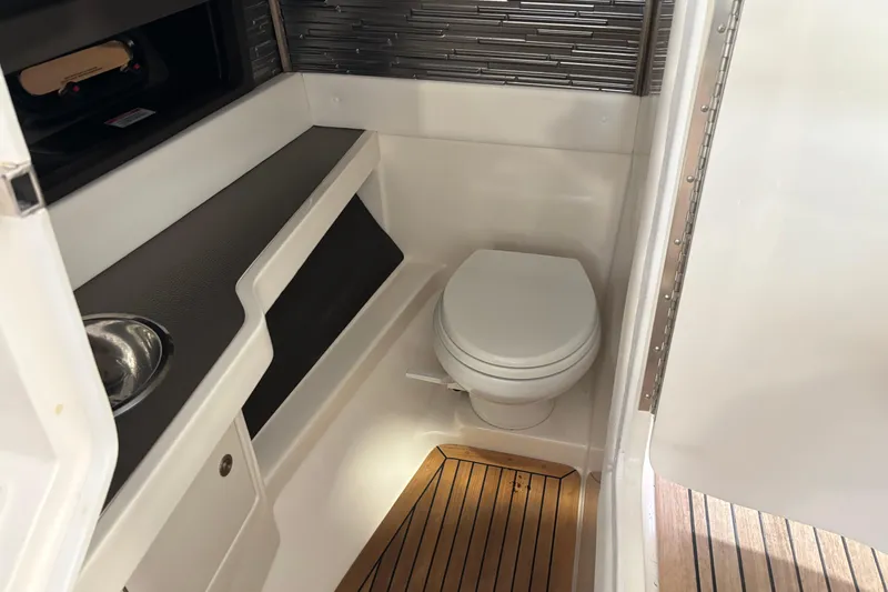 Slide: The Image of 2023 Sea Ray SLX 310 boat bathroom with toilet, sink, and wooden flooring. - 14