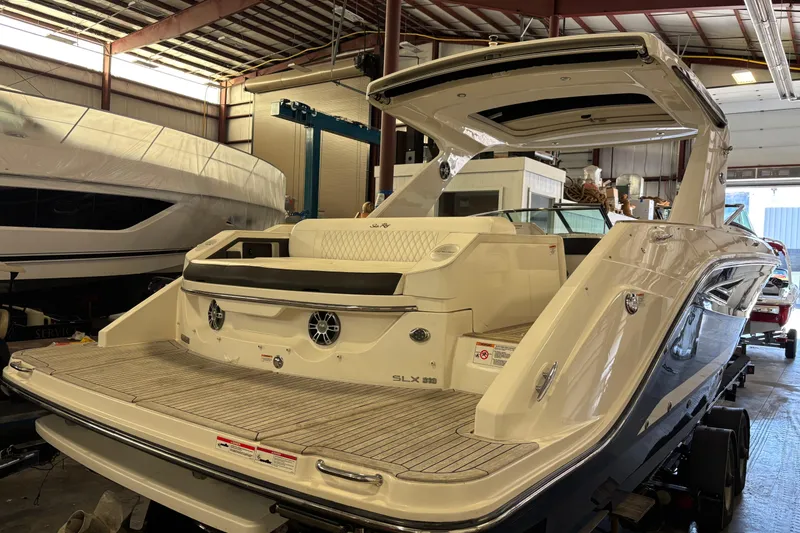 Slide: The Image of 2023 Sea Ray SLX 310 boat in a warehouse, showcasing sleek design and spacious deck. - 6