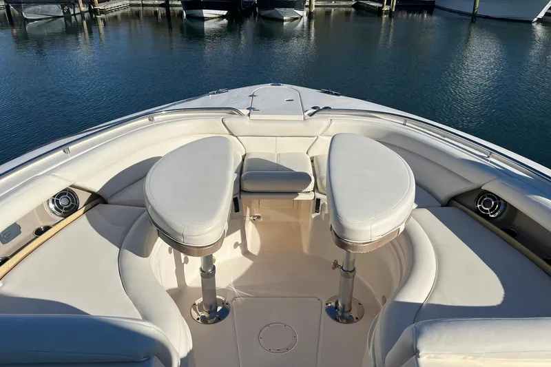 Slide: The Image of 2015 Grady-White Freedom 375 boat interior with plush seating and table, docked in marina. - 4