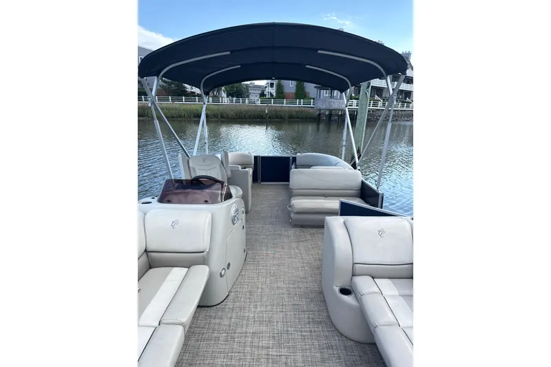 Slide: The Image of 2023 Cypress Cay Seabreeze 232 pontoon boat interior with seating and canopy on a calm waterway. - 3