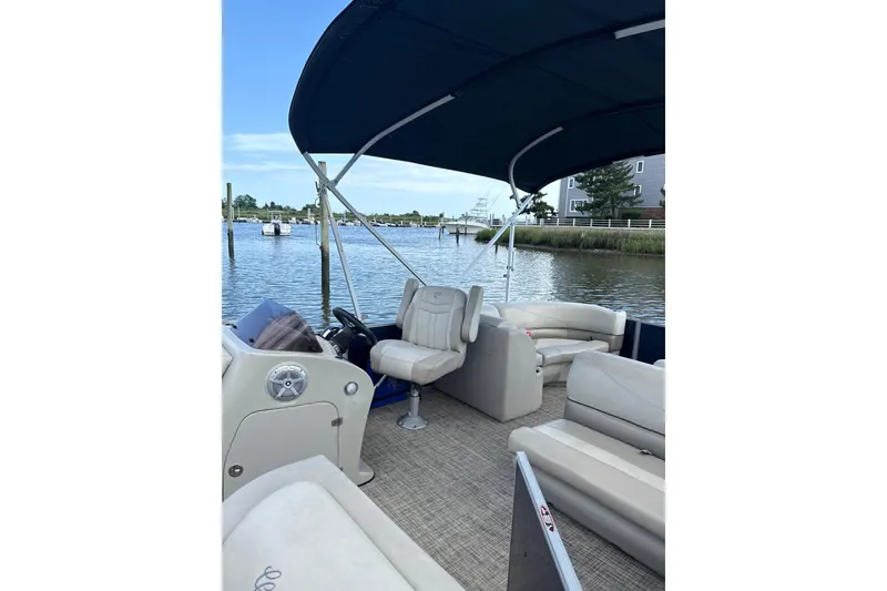 Slide: The Image of 2023 Cypress Cay Seabreeze 232 pontoon boat interior with canopy on a calm lake. - 5