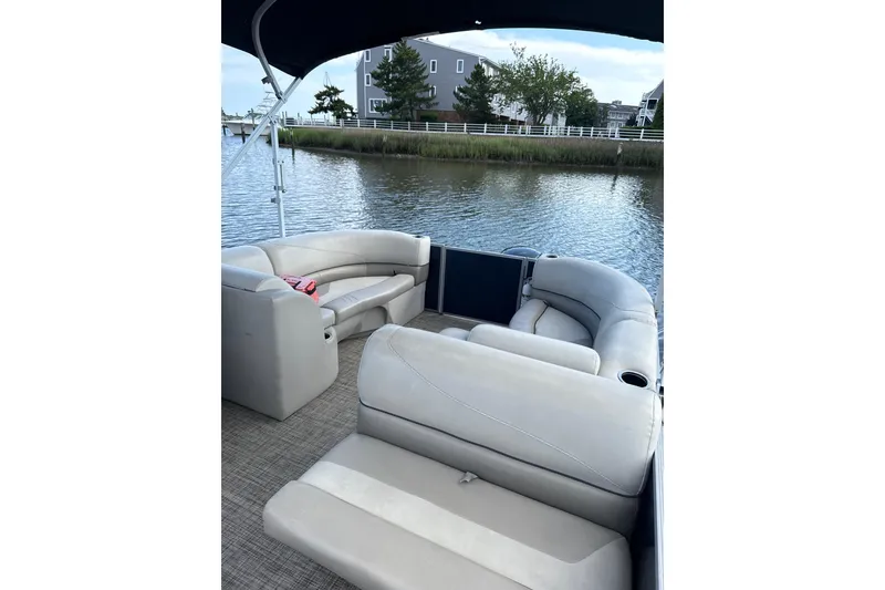 Slide: The Image of 2023 Cypress Cay Seabreeze 232 pontoon boat interior with plush seating on a calm waterway. - 8
