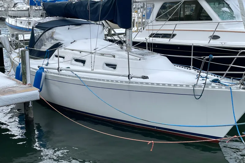The Image of 1987 J Boats J28 sailboat docked, covered in snow, with blue fenders and ropes. - 0