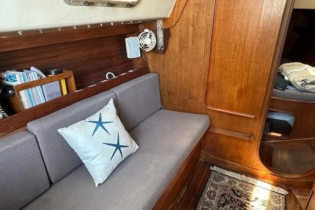 Slide: The Image of 1987 J Boats J28 interior with cushioned seating, starfish pillow, and wooden paneling. - 10