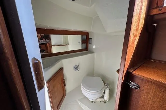 Slide: The Image of 1987 J Boats J28 yacht bathroom with toilet, mirror, and wooden cabinetry. - 16