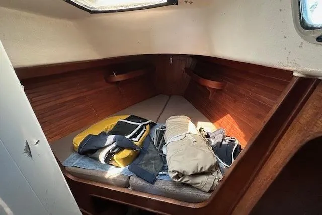 Slide: The Image of 1987 J Boats J28 cabin interior with wooden paneling and stored clothing. - 17
