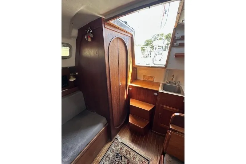 Slide: The Image of 1987 J Boats J28 interior with wooden cabinetry, seating, and small sink area. - 7