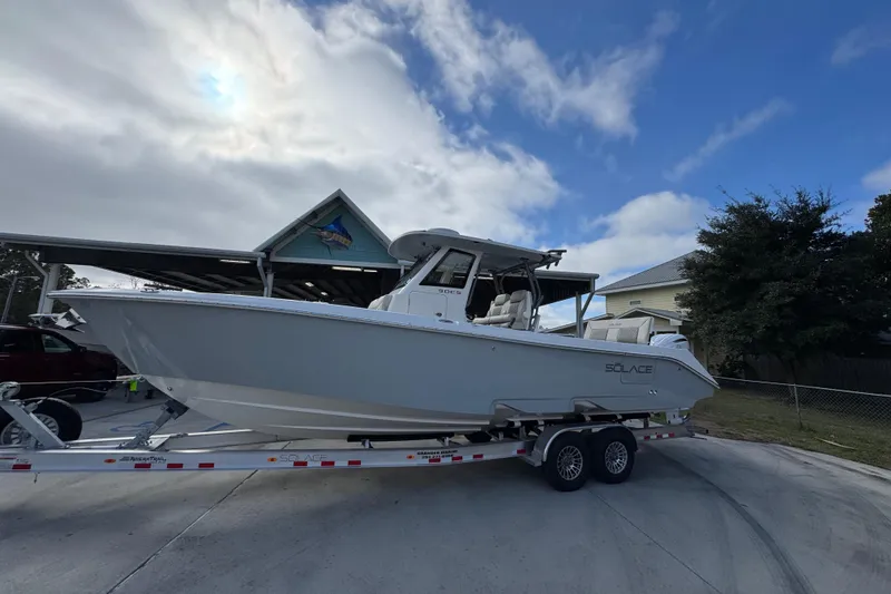 Slide: The Image of 2026 Solace 30 CS boat on trailer, parked outdoors under cloudy sky. - 2