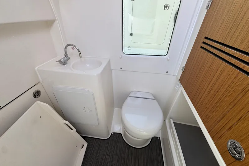 Slide: The Image of Compact bathroom in 2026 Solace 30 CS boat with sink, toilet, and wooden cabinet. - 30