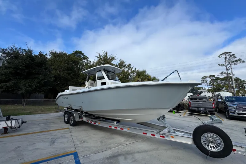 Slide: The Image of 2026 Solace 30 CS boat on trailer in parking lot, under blue sky. - 8
