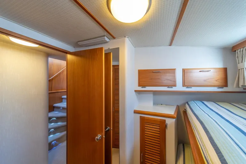 Slide: The Image of 1991 Tollycraft 57 Pilothouse Motor Yacht interior cabin with wooden accents and striped bedding. - 41