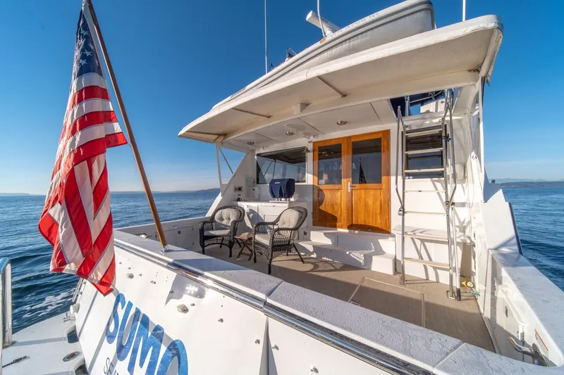Slide: The Image of 1991 Tollycraft 57 Pilothouse Motor Yacht with American flag, ocean view, and seating area. - 43