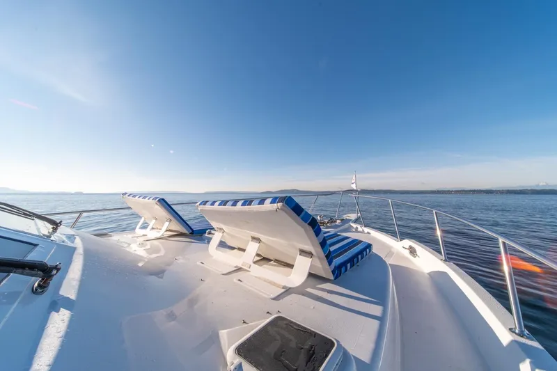 Slide: The Image of 1991 Tollycraft 57 Pilothouse Motor Yacht deck with striped lounge chairs on open water. - 48