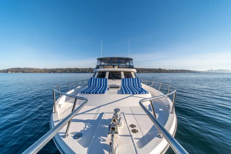 Slide: The Image of 1991 Tollycraft 57 Pilothouse Motor Yacht on calm water, featuring striped deck chairs. - 49