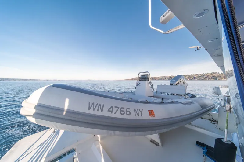 Slide: The Image of 1991 Tollycraft 57 Pilothouse Motor Yacht with inflatable boat on deck, scenic water view. - 60