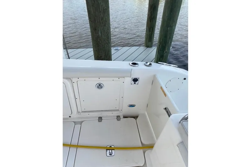 Slide: The Image of 2005 Century 2900 Center Console boat interior near dock, showcasing storage and seating area. - 19