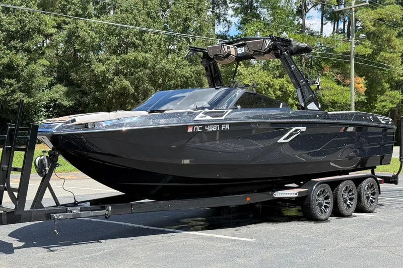 Slide: The Image of 2023 Centurion Ri265 boat on trailer, parked outdoors with trees in background. - 18