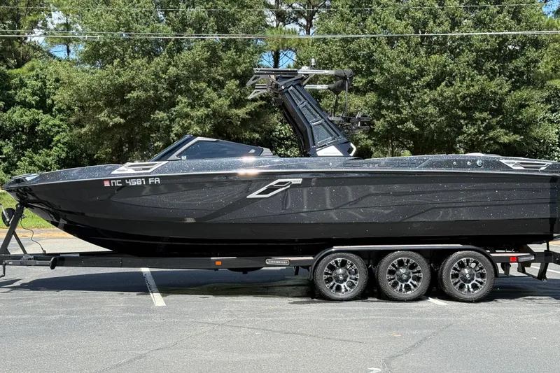 Slide: The Image of 2023 Centurion Ri265 boat on trailer, parked outdoors with trees in background. - 19