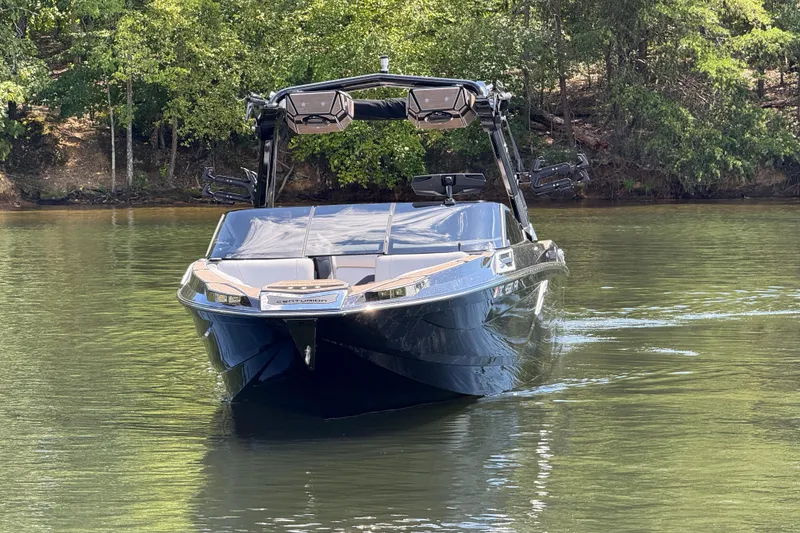 Slide: The Image of 2023 Centurion Ri265 boat cruising on a serene lake with lush green trees. - 2