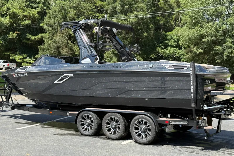 Slide: The Image of 2023 Centurion Ri265 boat on trailer, parked outdoors with lush green background. - 20