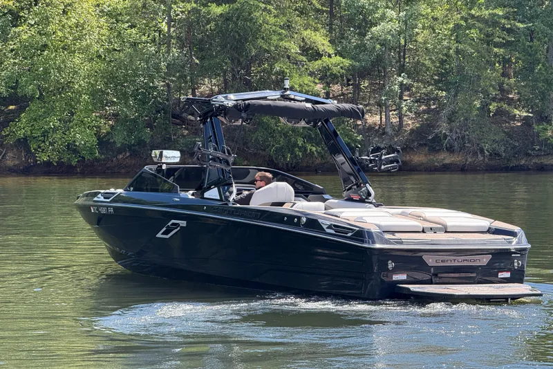 Slide: The Image of 2023 Centurion Ri265 boat cruising on a serene lake with lush green trees. - 5