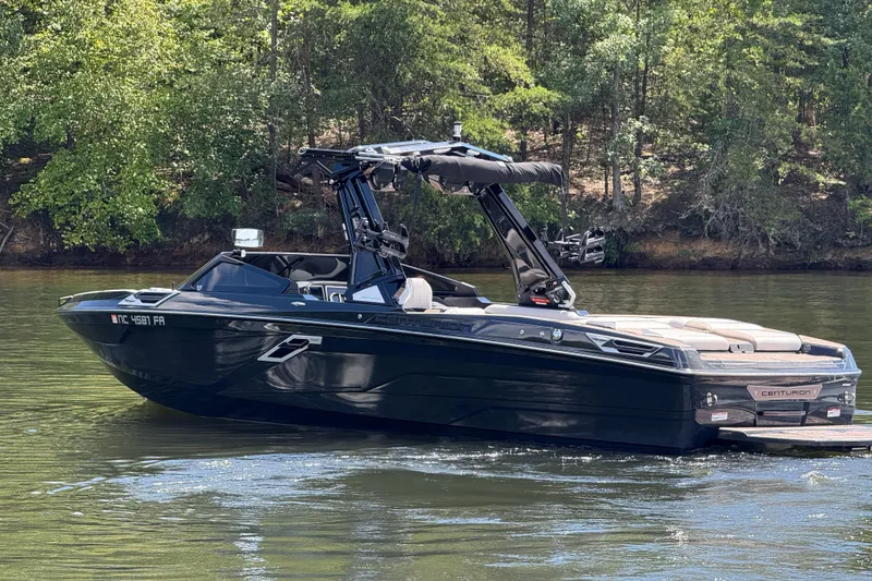 Slide: The Image of 2023 Centurion Ri265 boat on a serene lake with lush green trees. - 6