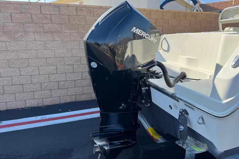 Slide: The Image of 2022 Sailfish 242 CC boat with Mercury outboard motor, parked near brick wall. - 6