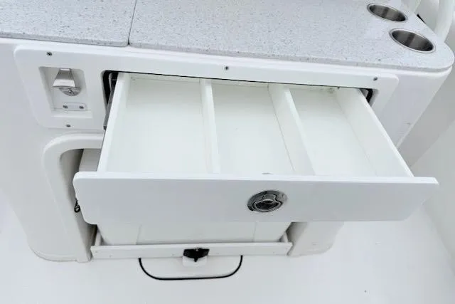Slide: The Image of Open storage drawer on 2026 Tidewater 256 CC Adventure boat, featuring cup holders. - 9