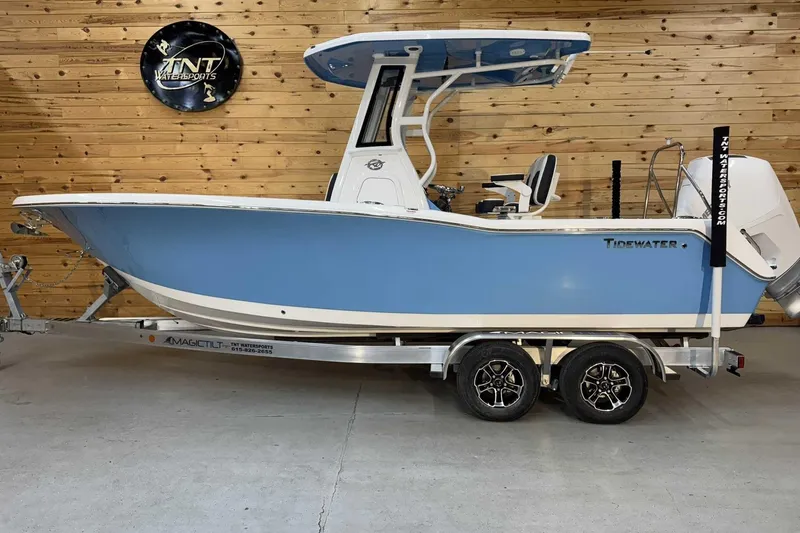 The Image of 2025 Tidewater 232 CC Adventure boat in showroom, blue hull, on trailer. - 1