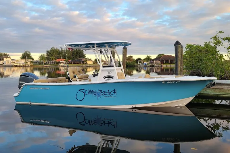 The Image of 2019 Sportsman Heritage 241 Center Console boat on clear blue water near sandy beach. - 0