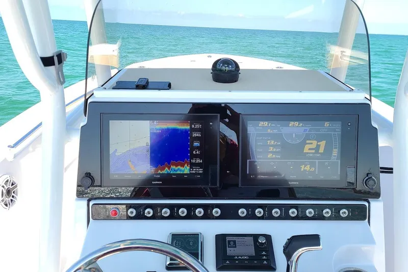 Slide: The Image of 2019 Sportsman Heritage 241 Center Console boat docked, featuring beige seating and modern controls. - 13