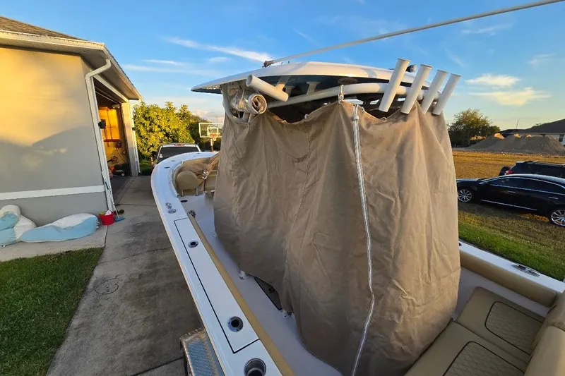 Slide: The Image of 2019 Sportsman Heritage 241 Center Console boat with protective cover, parked in driveway. - 33