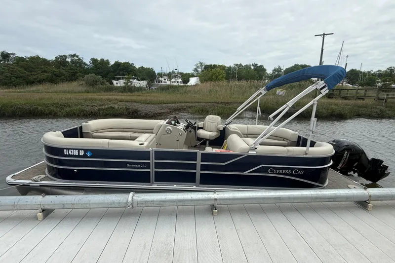 The Image of 2023 Cypress Cay Seabreeze 232 pontoon boat docked by a scenic riverside. - 1