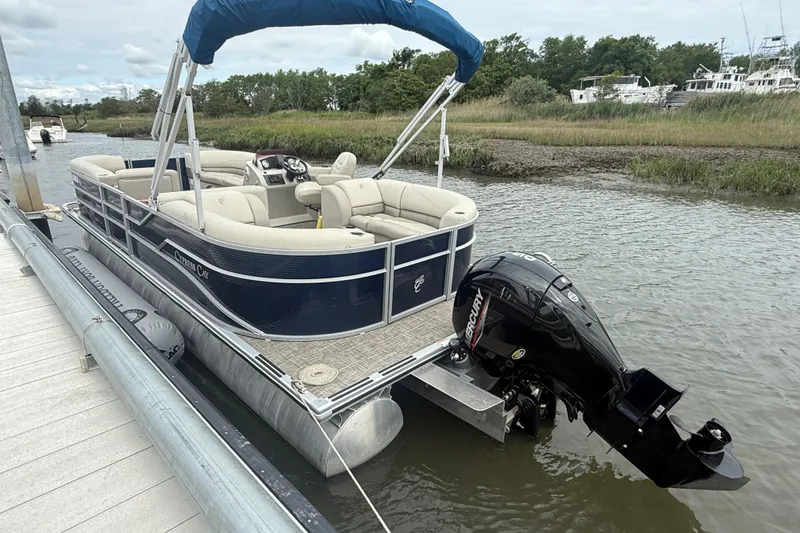 Slide: The Image of 2023 Cypress Cay Seabreeze 232 pontoon boat docked, featuring a Mercury outboard motor. - 2
