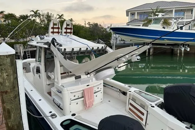Slide: The Image of 2020 Solace 345 CC boat docked, featuring fishing rods and a hammock setup. - 18