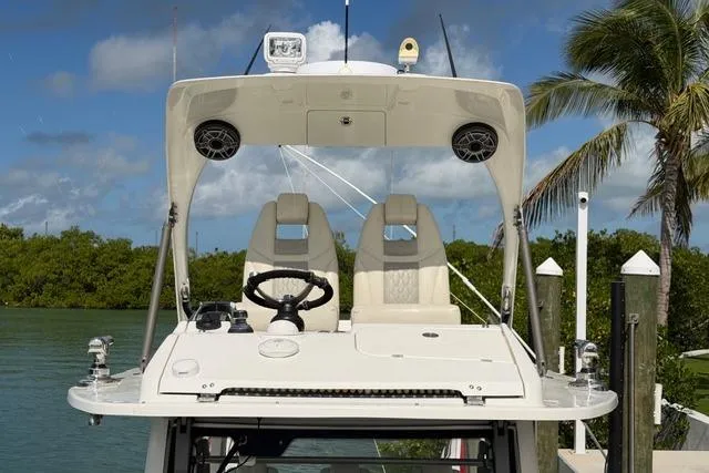 Slide: The Image of 2020 Solace 345 CC boat helm with dual seats, steering wheel, and canopy in tropical setting. - 7