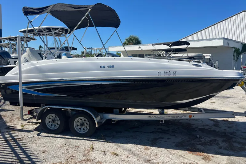 The Image of 2021 Hurricane SunDeck Sport 188 OB boat on trailer, with canopy, parked outdoors. - 0