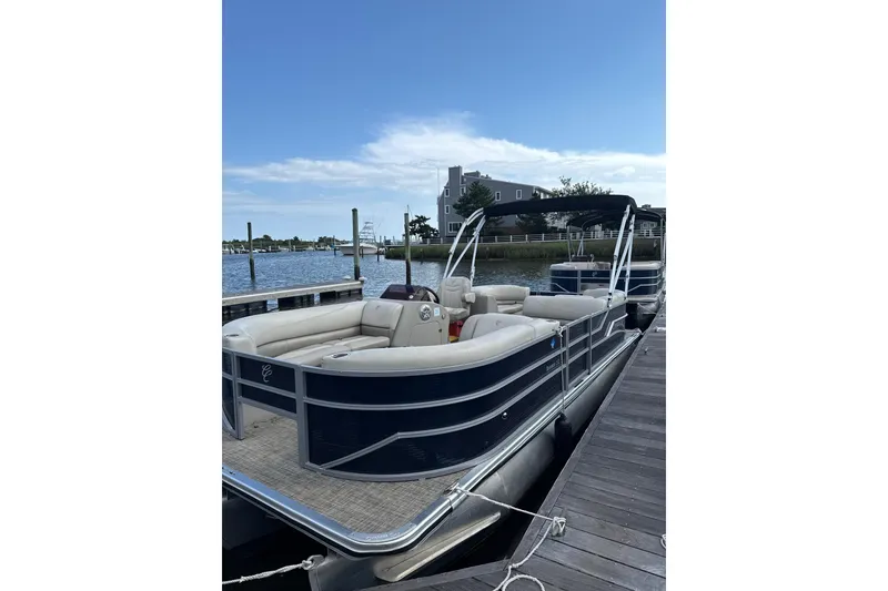 The Image of 2023 Cypress Cay Seabreeze 232 pontoon boat docked by a serene waterfront. - 1