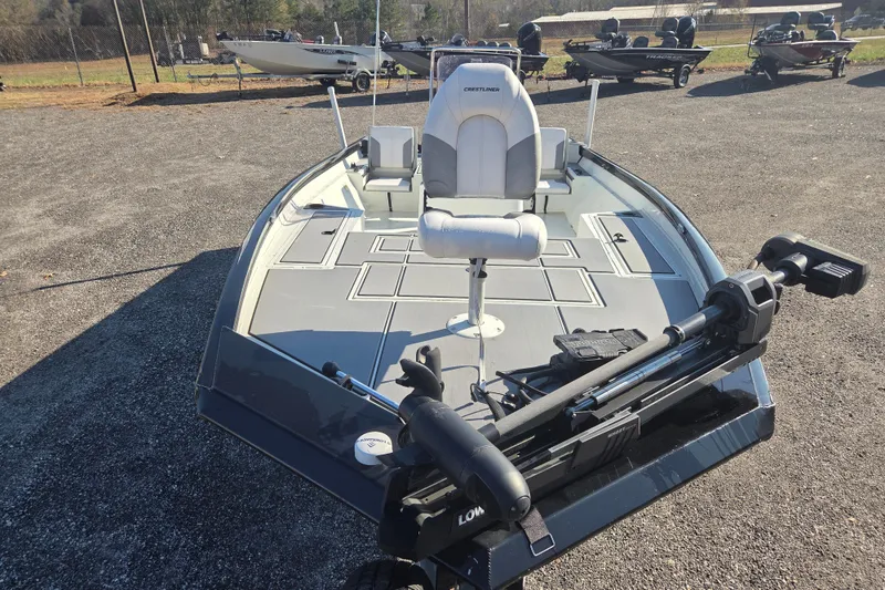 Slide: The Image of 2020 Crestliner 2000 Bay boat with trolling motor and fishing seat on gravel lot. - 2