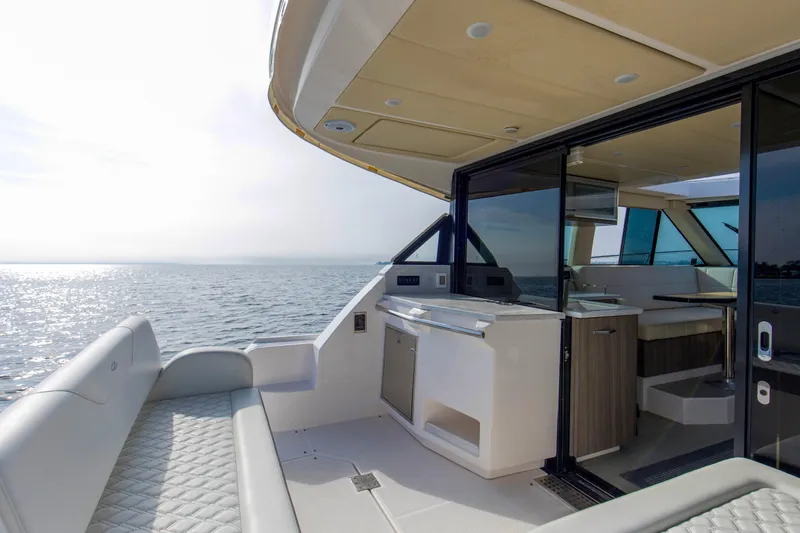 Slide: The Image of 2020 Regal 38 XO yacht interior with ocean view, featuring modern seating and kitchenette. - 24