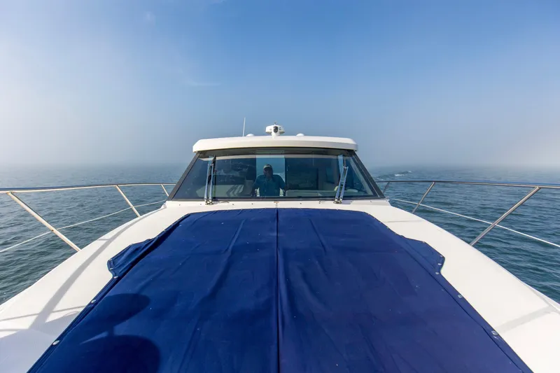 Slide: The Image of 2020 Regal 38 XO yacht cruising on open water under clear blue sky. - 45