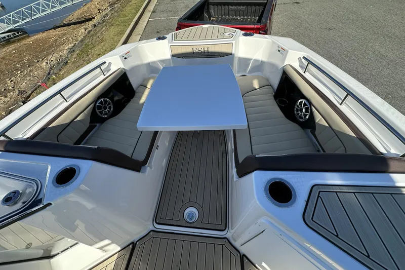 Slide: The Image of 2023 Yamaha Boats 252 FSH Sport interior with seating and table, dockside view. - 15