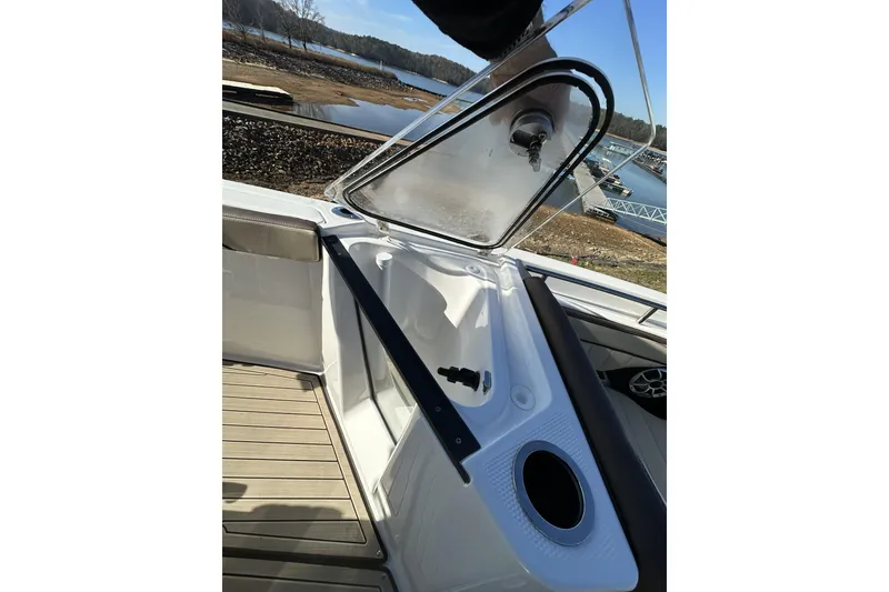 Slide: The Image of 2023 Yamaha Boats 252 FSH Sport interior with open storage compartment and scenic water view. - 19