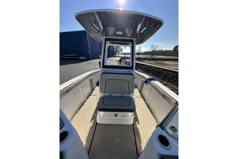 Slide: The Image of 2023 Yamaha Boats 252 FSH Sport interior with seating and console, under sunny sky. - 21
